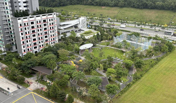 Overhead view of a park adjacent to a multistory building and a highway.